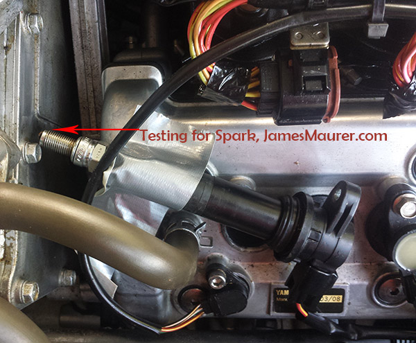 Spark plug test on Yamaha Waverunner - plug held against engine block to confirm spark